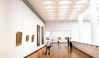 picture of a gallery hall with people viewing paintings