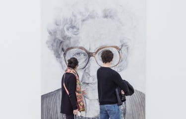 a picture of two people looking at a painting in front of them