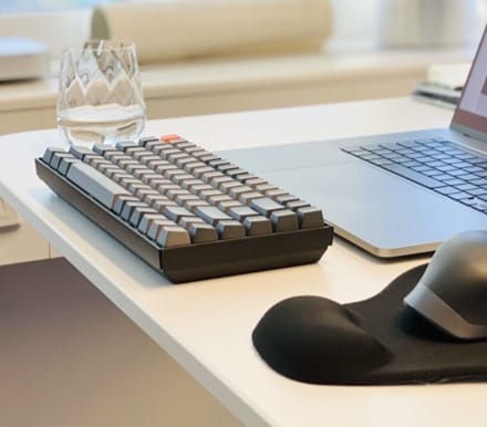 picture of a glass of water with a keyboard and mouse next to it and a laptop in front of the keyboard